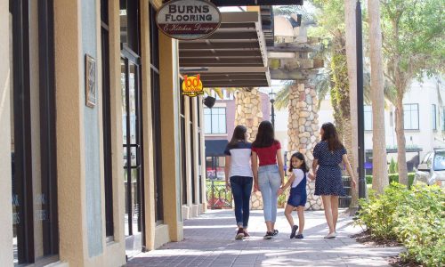 Mother and 3 daughters walking along sidewalk, in front of stores and restaurants at Lakeside Village in Lakeland.