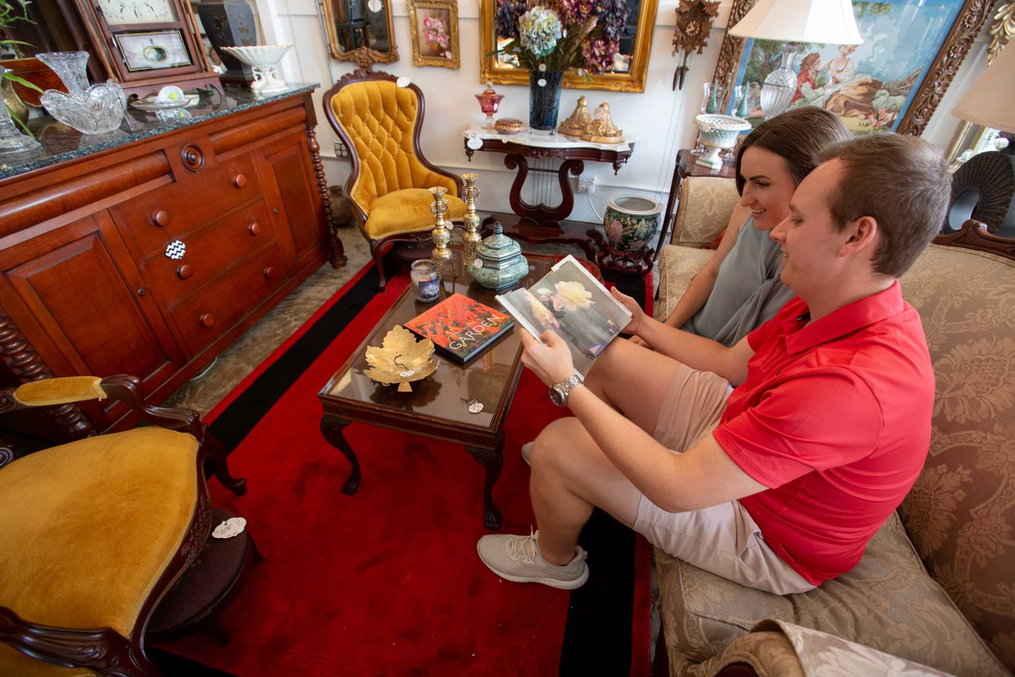 Couple looking at coffee table book while sitting on antique couch at Low Country Vintage in Lakeland, FL