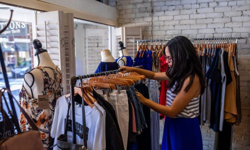 woman looking through clothes at Top Buttons Boutique and Designer Thrift