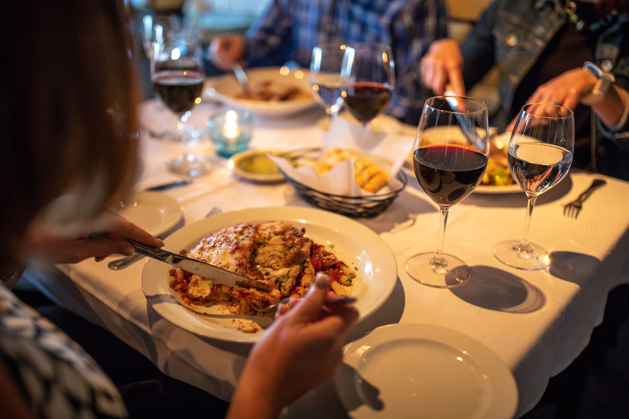 3 people eating Italian dishes, water and wine glasses at Scarpa's Italian in Lakeland, FL