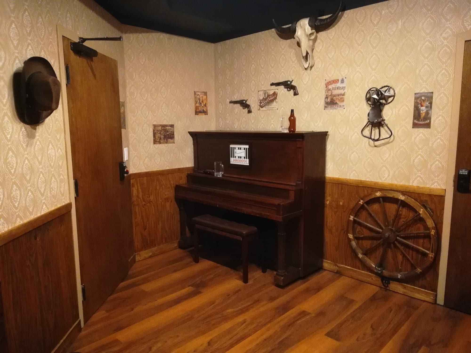 Arizona Shootout room with upright piano, wagon wheel and hanging skull at Escapology Escape Rooms in Lakeland, FL