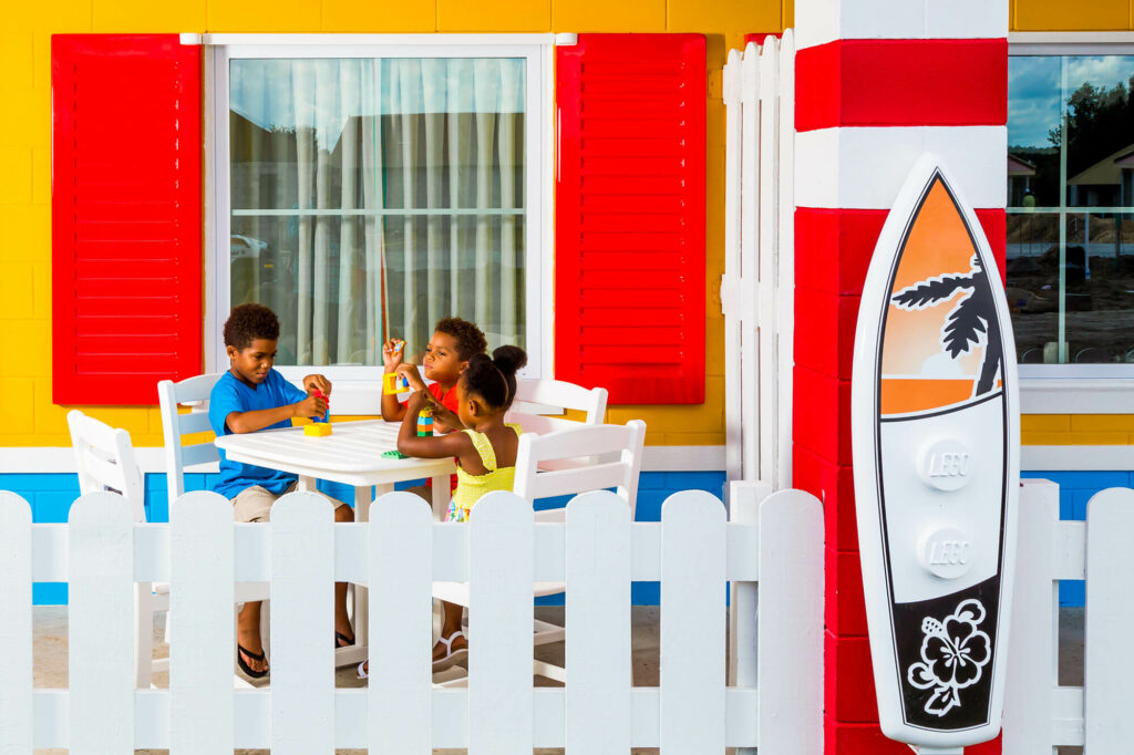 3 kids sitting at front porch table outside LEGOLAND Beach Retreat bungalow
